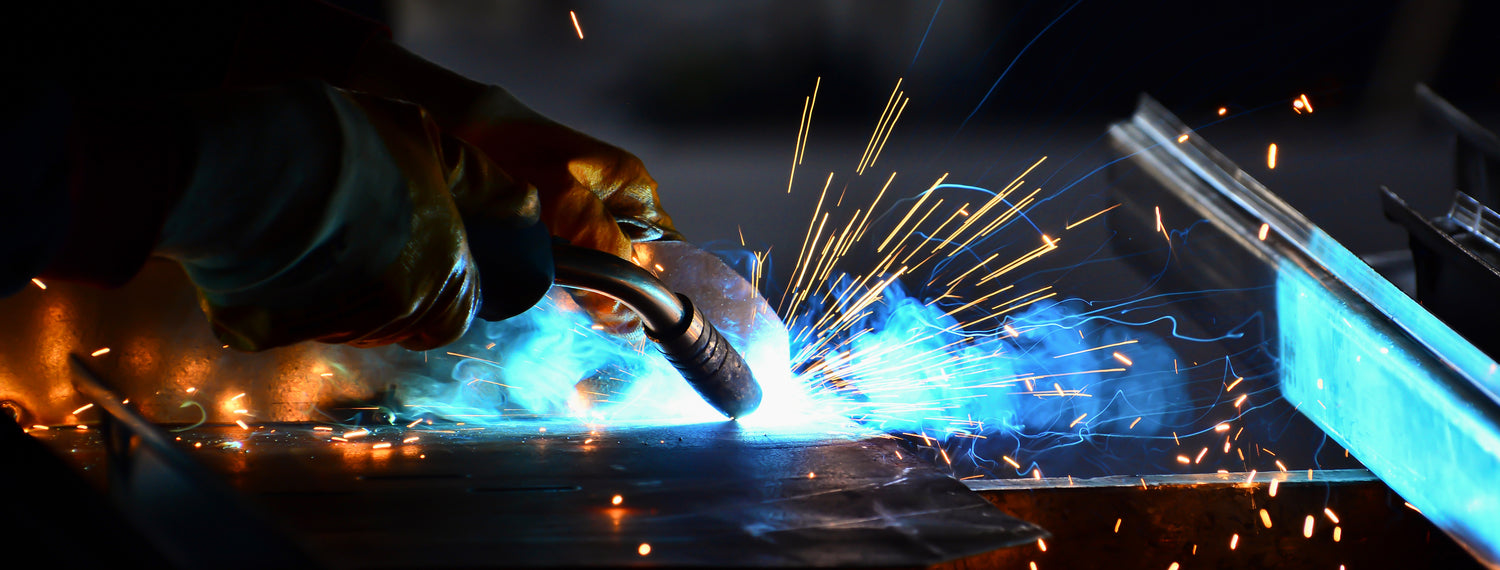Hands wearing welding gloves welding a piece of metal
